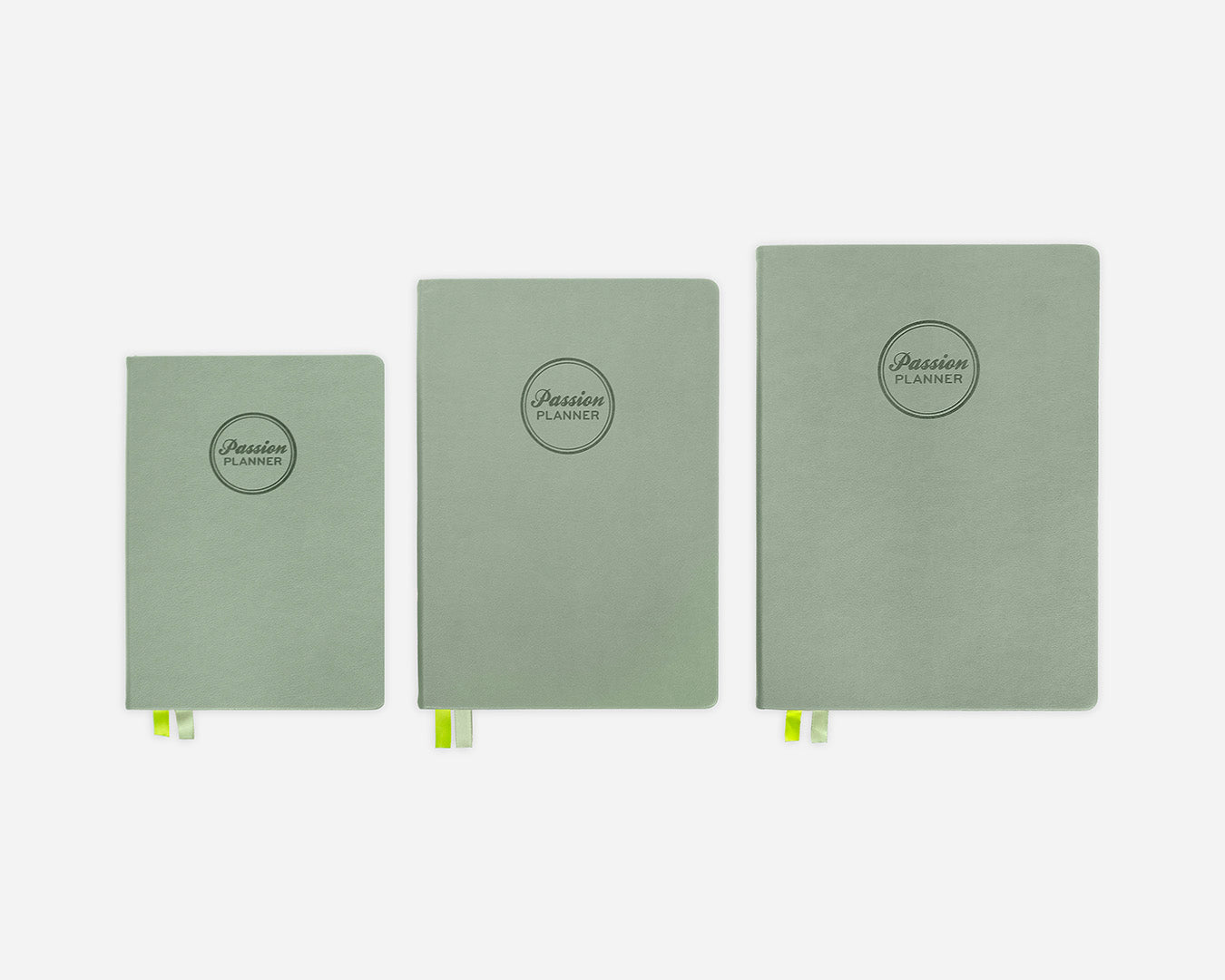 Three green hardcover planners of different sizes on a white background