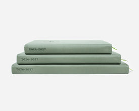 Three green planners stacked on a white background with '2026-2027' on the spines.