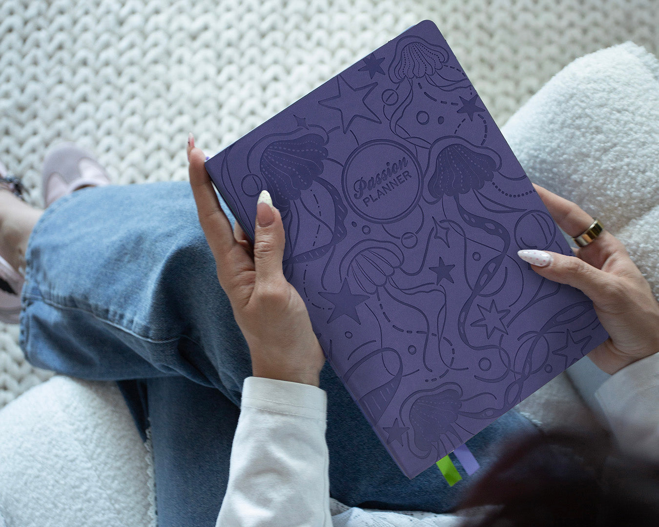 Purple planner with starry jellyfish design held by a person on a textured surface