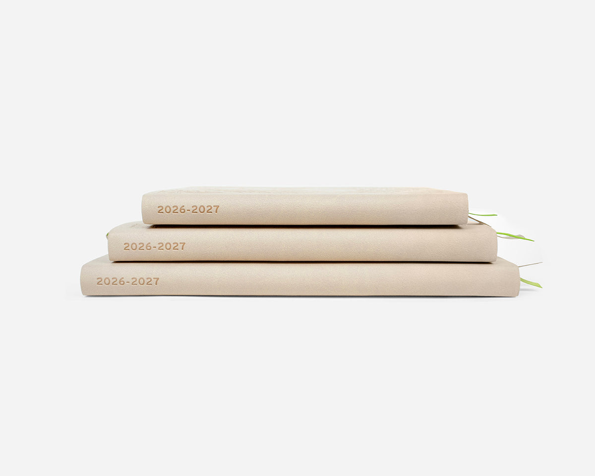 Three beige planners stacked on a white background with '2026-2027' on the spines.