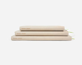 Three beige planners stacked on a white background with '2026-2027' on the spines.