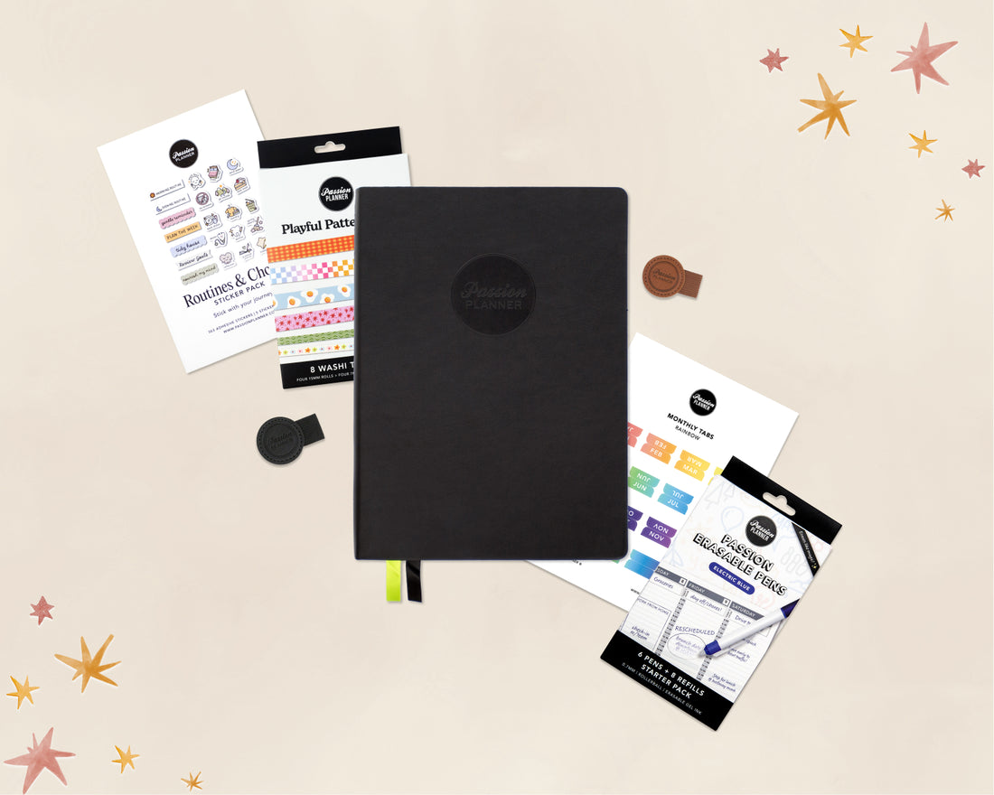 A black 2027 planner with a circular logo on the cover, shown with several stationery accessories and stickers around it on a light beige background with star illustrations. Visible branding includes &