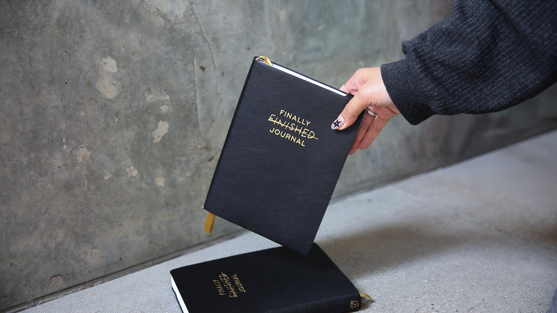 Person holding a black journal titled &