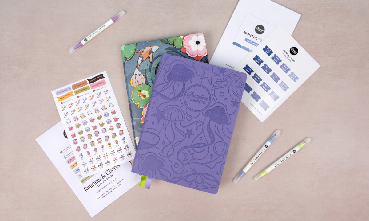Purple mid-year planner, icon stickers, and stationery items on a beige surface