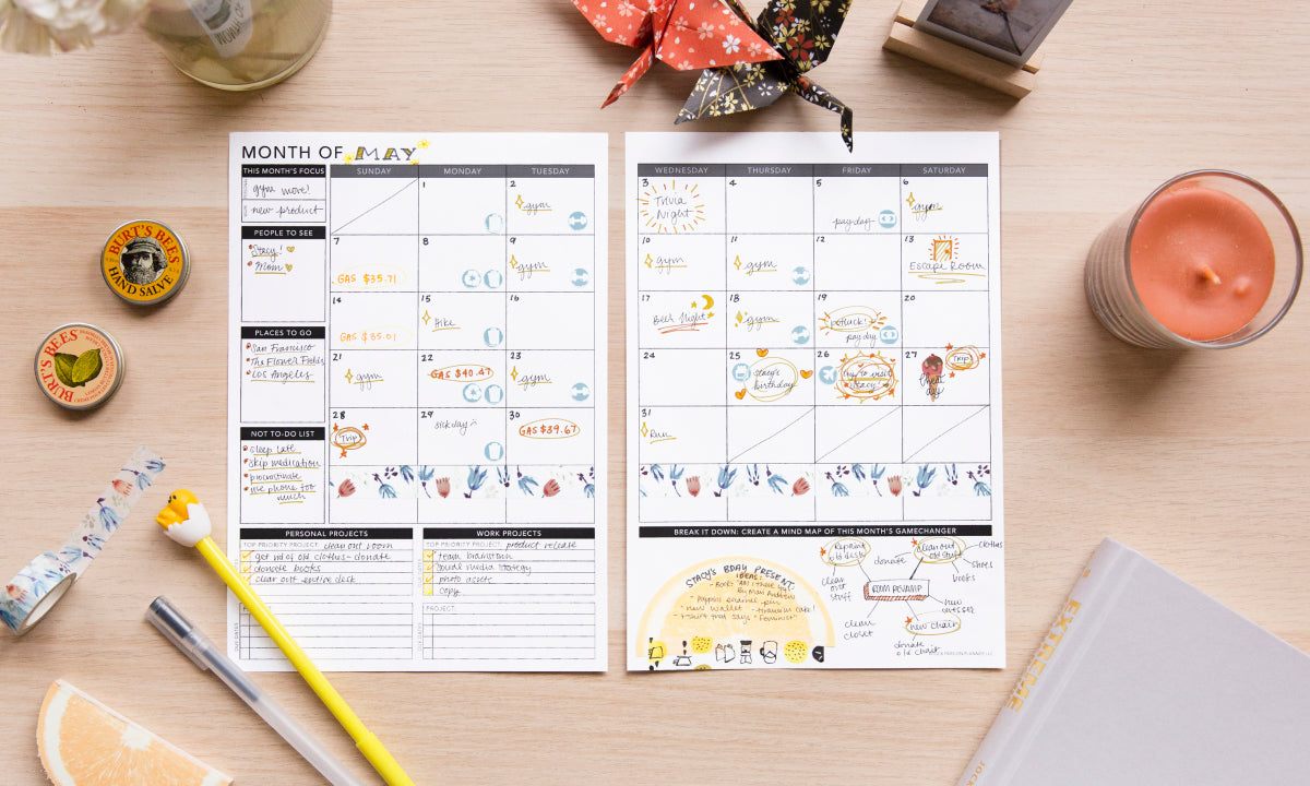Two printable planner pages on a wooden desk with stationery items around