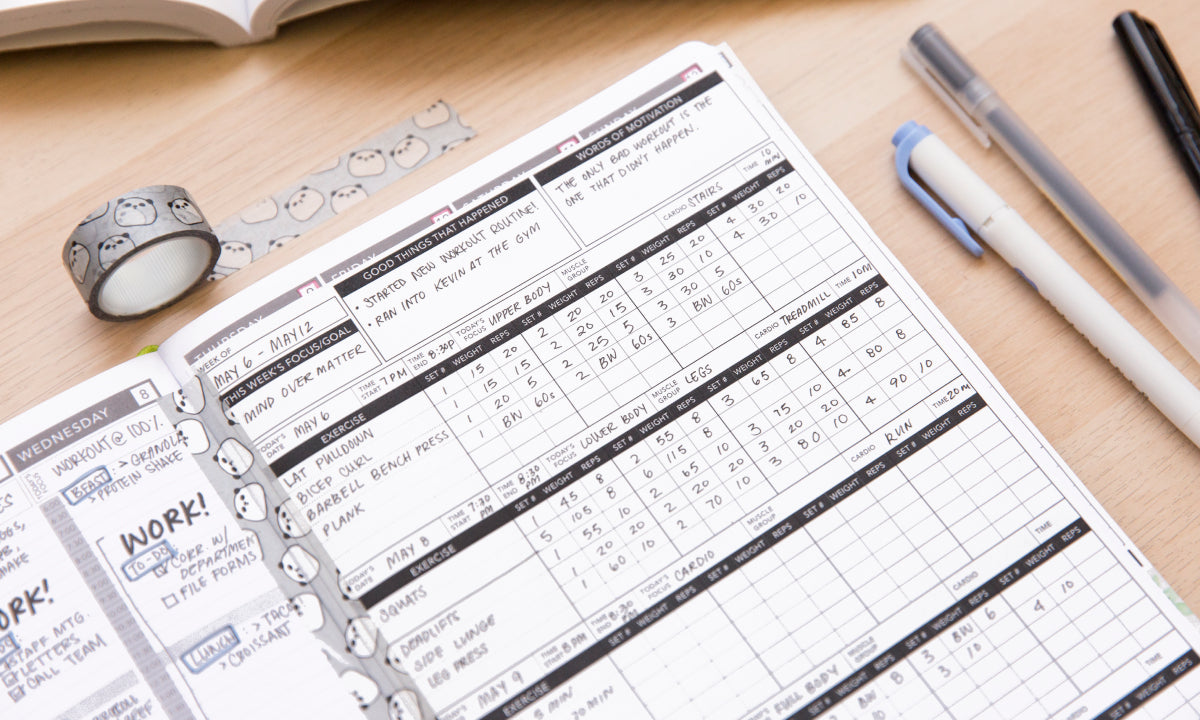 Open planner with daily schedule on a wooden desk with pens and washi tape.