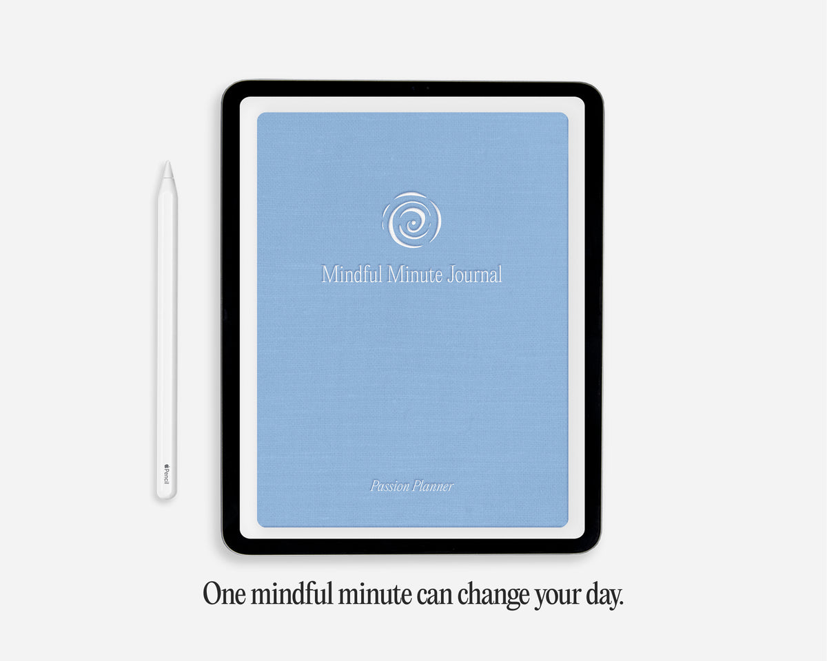 A tablet-style digital journal cover with a light blue front and black border, shown on a light gray background with a white stylus beside it and the text 'One mindful minute can change your day.' below.