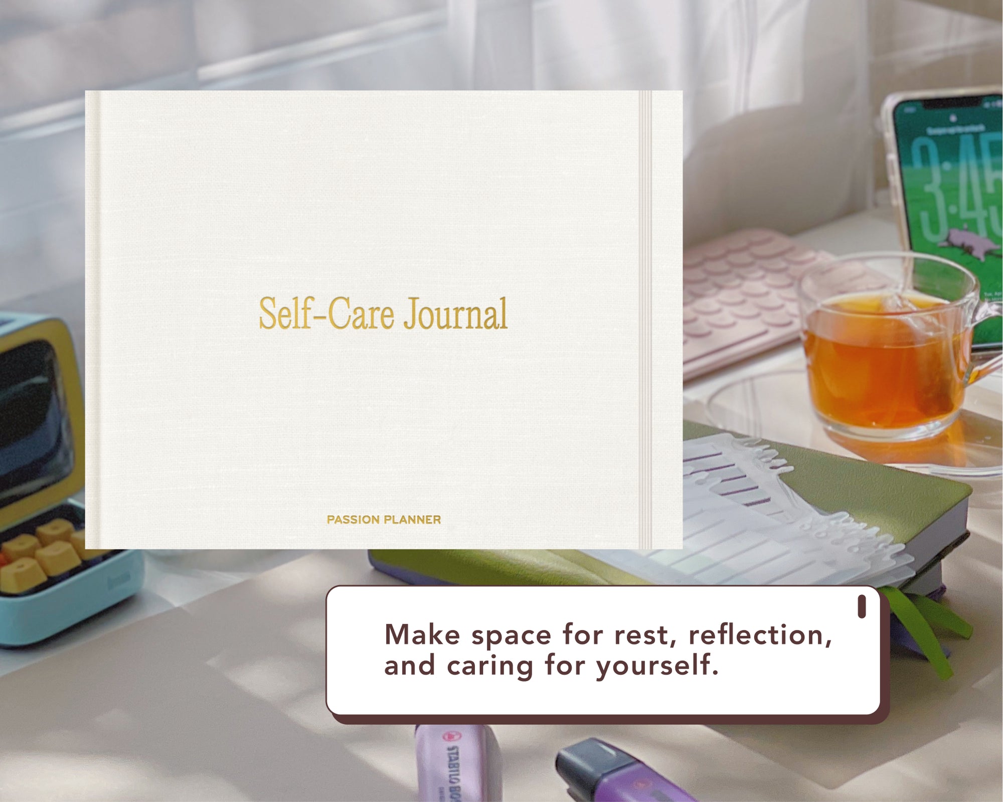 A white digital Self-Care Journal with gold lettering is shown in a styled desk setting with a glass of tea, a smartphone, and other office accessories. A text box at the bottom reads, 'Make space for rest, reflection, and caring for yourself.