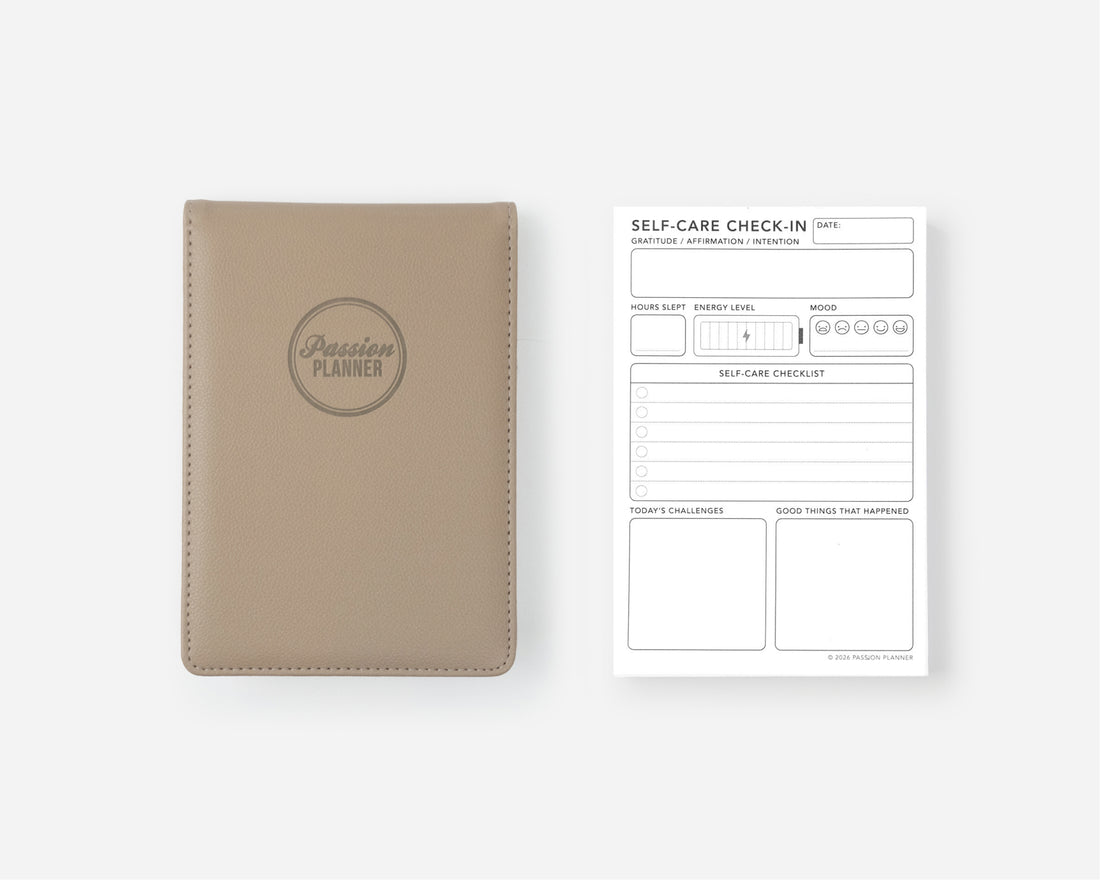 A beige leather-bound notepad shown next to a white &
