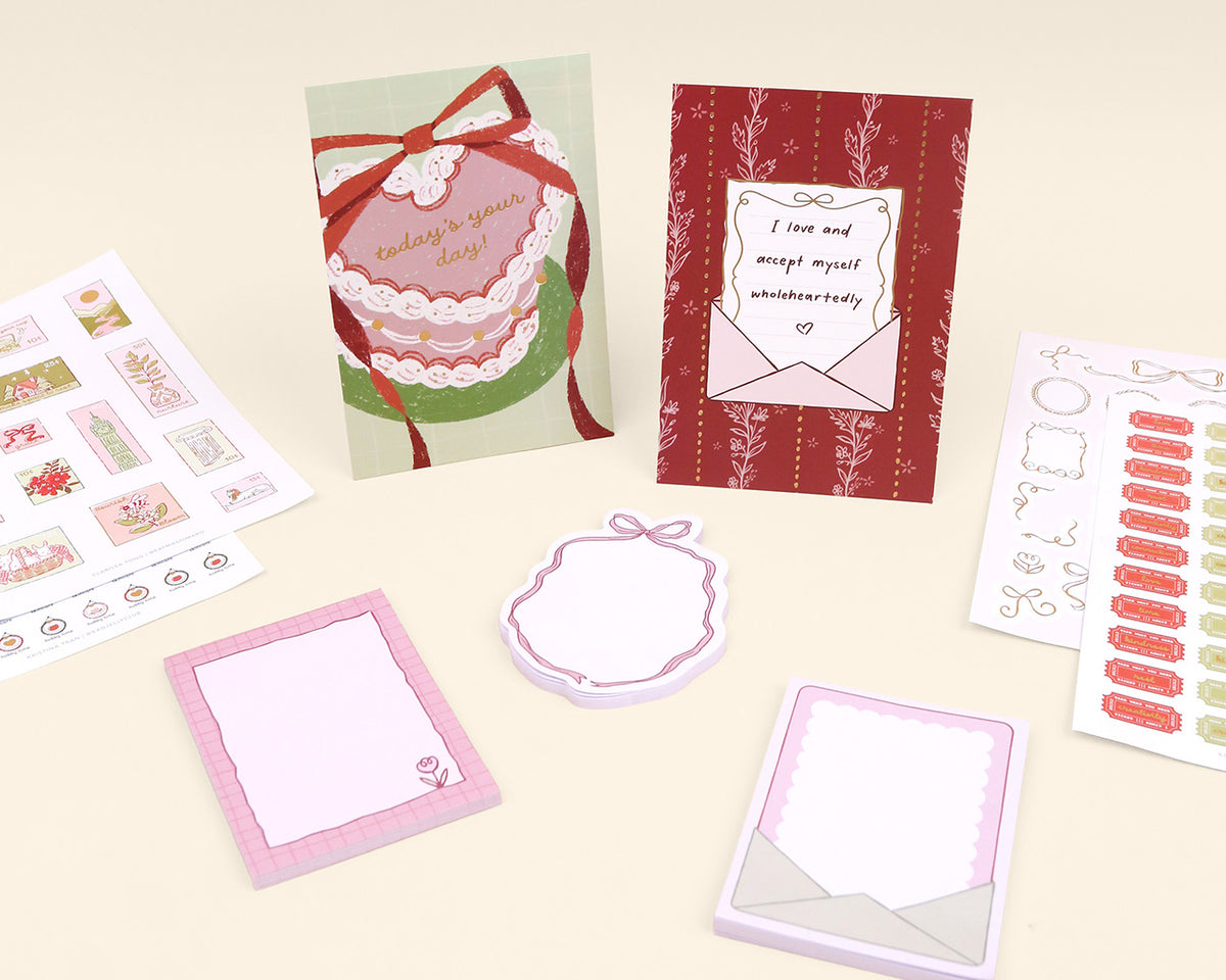 Collection of stationery items including cards, notepads, and stickers on a light background