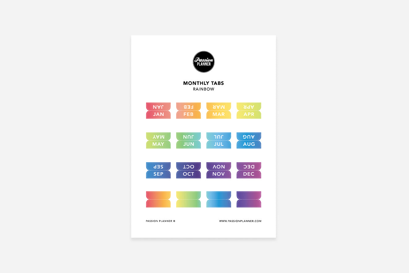 A sheet of rainbow colored monthly tabs labeled with different months of the year, designed to be used in a planner.